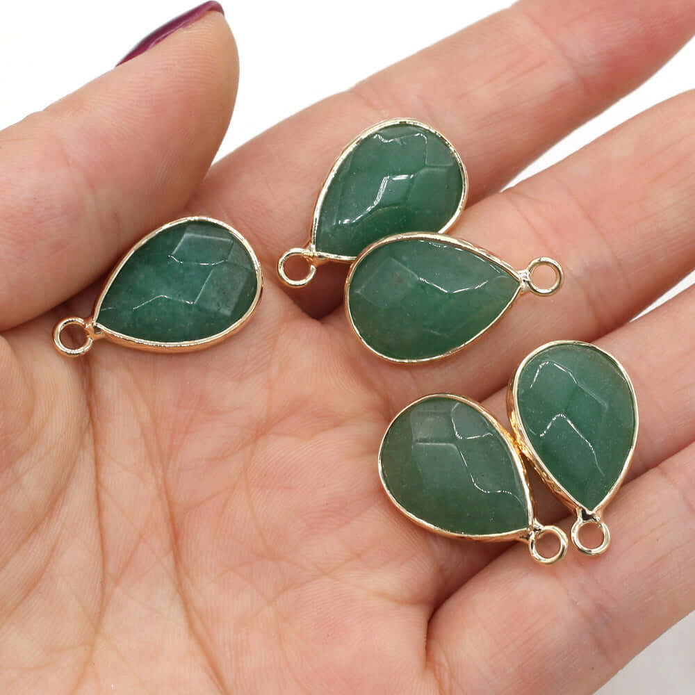 Handmade green Dongling jade drop-shaped pendants in a hand, perfect for DIY jewelry projects.