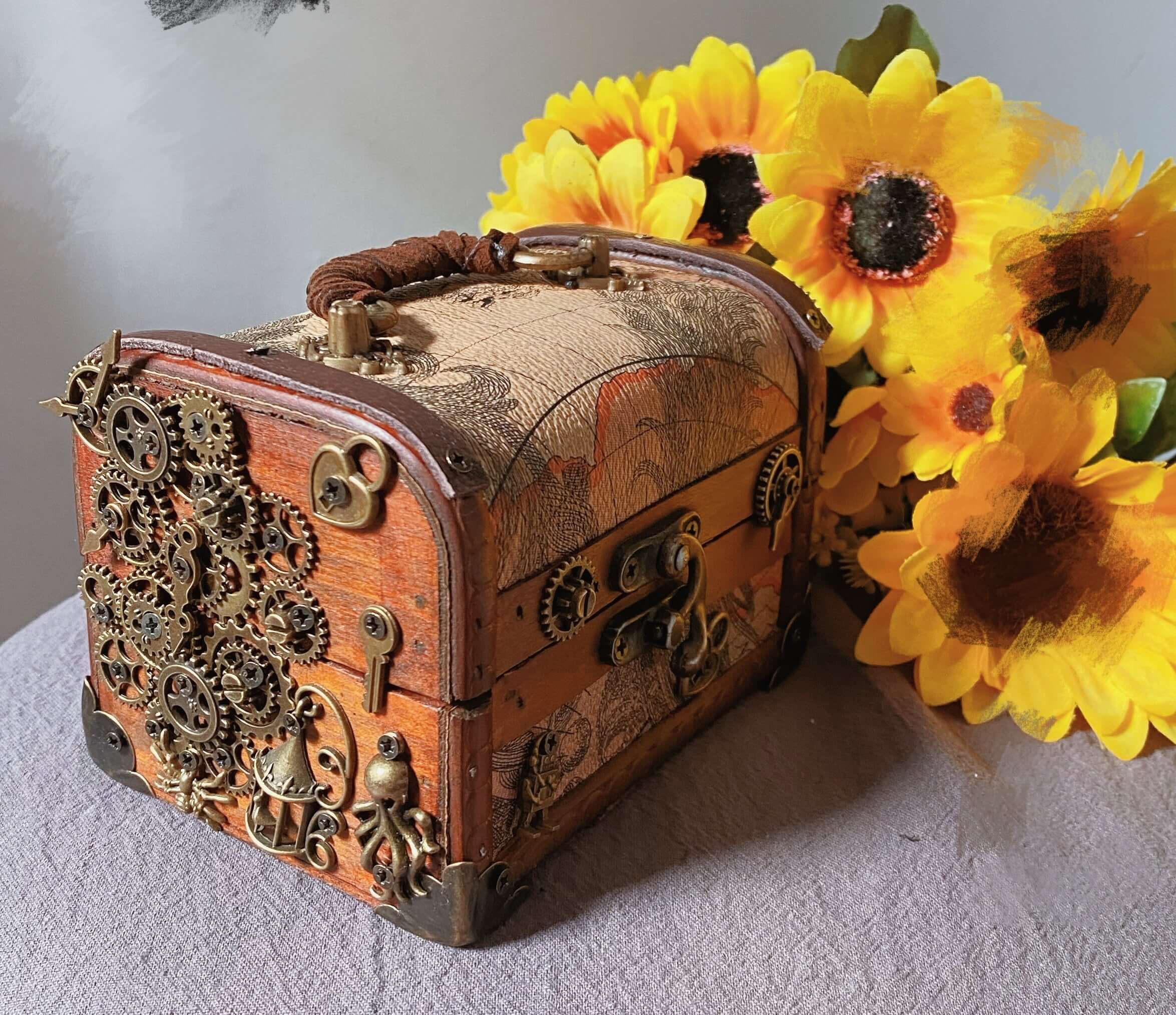 Handmade wooden jewelry box with steampunk design and gears, surrounded by bright sunflowers.