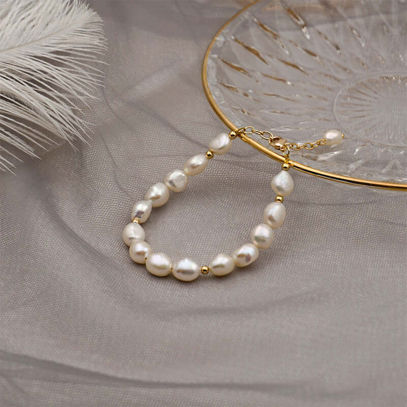 Handmade baroque pearl bracelet on a glass plate, featuring natural freshwater pearls and gold accents.