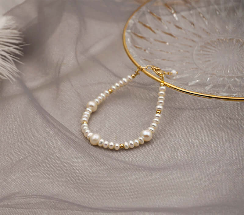 Simple handmade bracelet featuring natural baroque pearls and copper accents, displayed on an elegant glass plate.