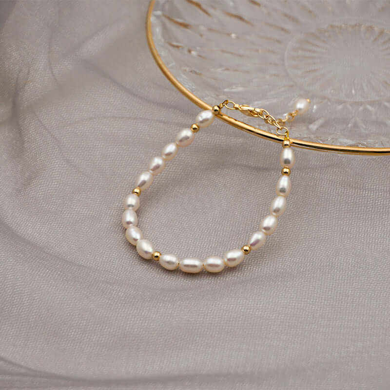 Handmade baroque pearl bracelet on a gold dish, featuring natural freshwater pearls and copper accents.